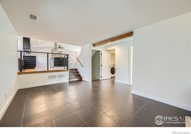 unfurnished living room featuring stairway, washer / clothes dryer, visible vents, and dark tile patterned flooring