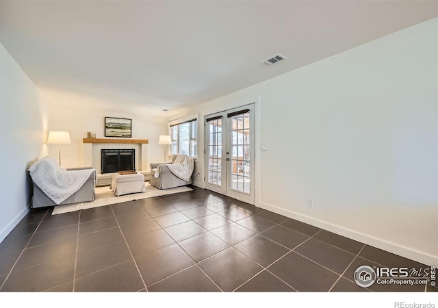 unfurnished room featuring visible vents, dark tile patterned flooring, a fireplace, and french doors