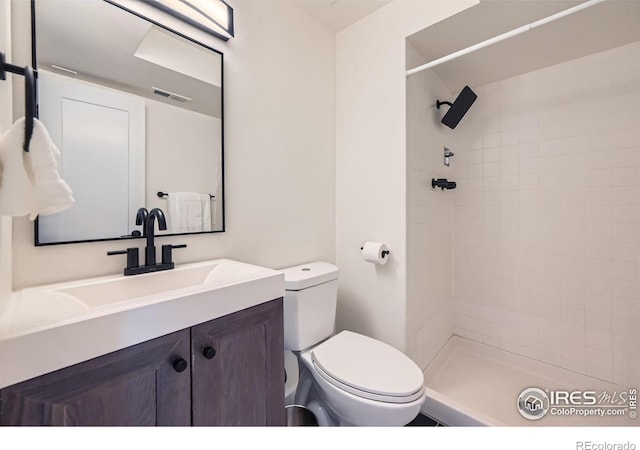 full bathroom featuring tiled shower, toilet, vanity, and visible vents