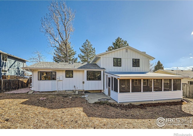 rear view of property featuring board and batten siding, fence, and a sunroom