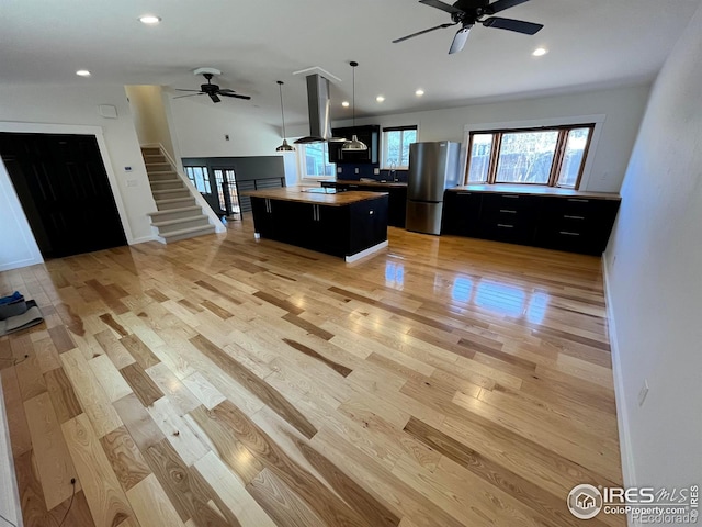 kitchen with dark cabinetry, freestanding refrigerator, light wood-style floors, open floor plan, and a center island