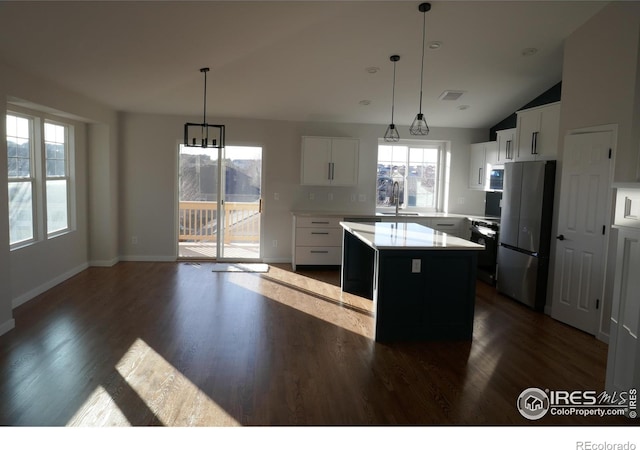 kitchen with stainless steel refrigerator, decorative light fixtures, a kitchen island, and white cabinets