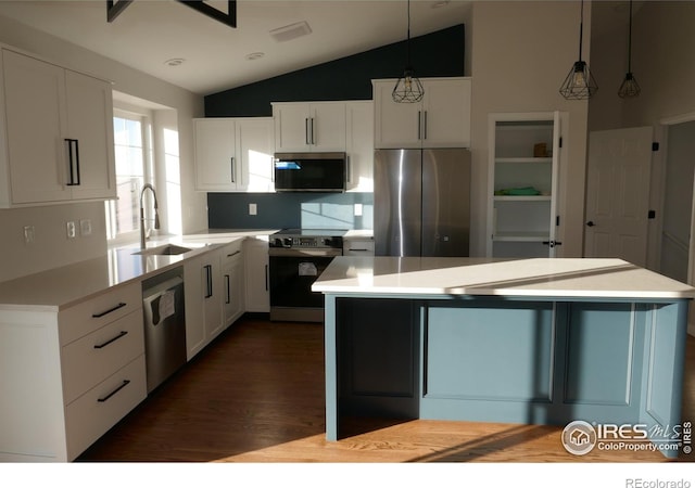 kitchen with stainless steel appliances, white cabinetry, sink, and decorative light fixtures