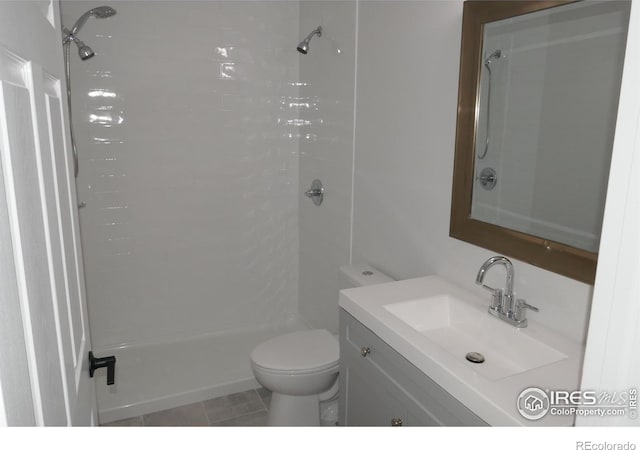 bathroom with vanity, tiled shower, tile patterned floors, and toilet