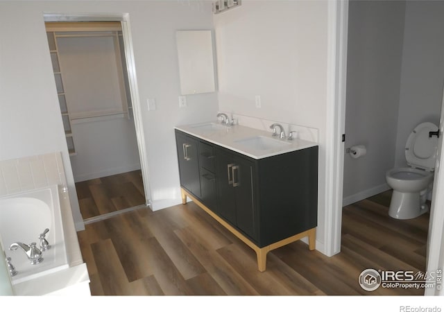 bathroom with hardwood / wood-style flooring, vanity, a tub, and toilet