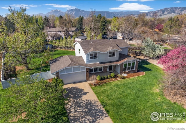 view of front facade featuring a garage, a mountain view, and a front lawn