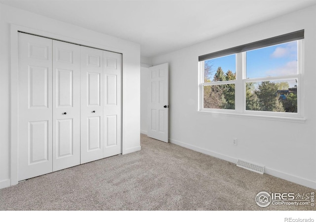 unfurnished bedroom with a closet and light carpet