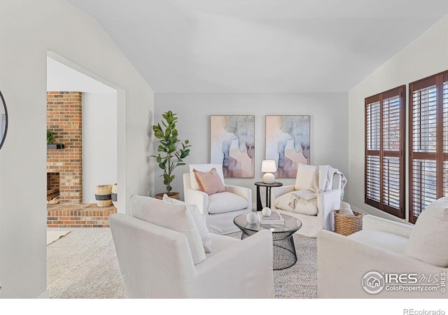 living room featuring lofted ceiling and a brick fireplace