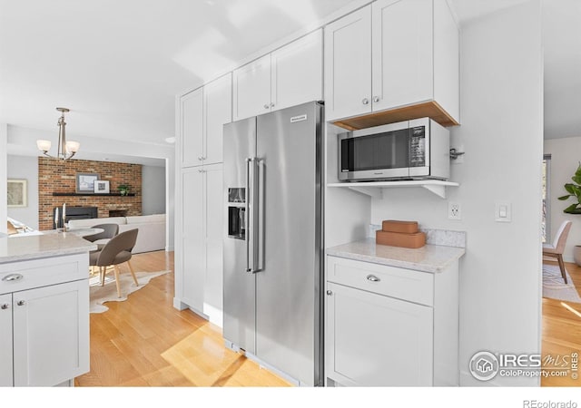 kitchen featuring white cabinetry, light stone counters, stainless steel appliances, and light wood-type flooring