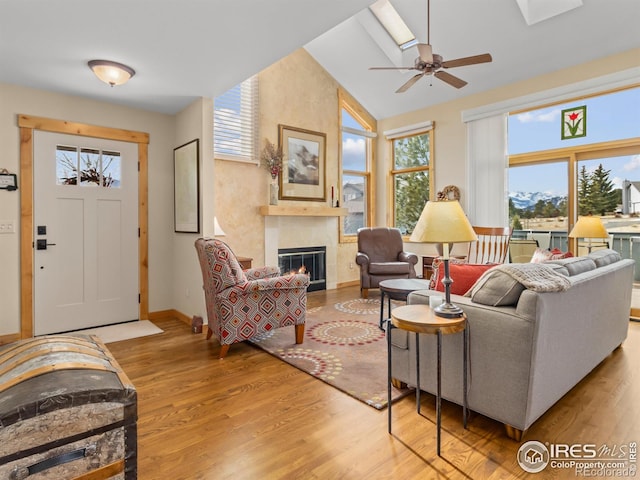 living room with a tiled fireplace, ceiling fan, lofted ceiling, and light hardwood / wood-style floors