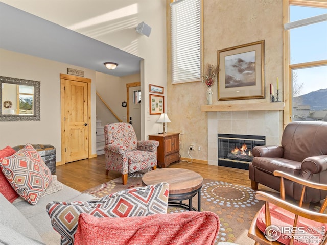 living room with a tiled fireplace, hardwood / wood-style flooring, and a healthy amount of sunlight