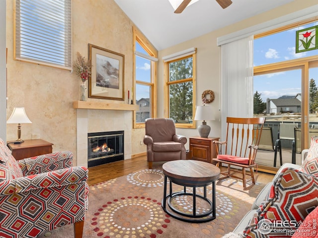 living room featuring wood-type flooring, vaulted ceiling, ceiling fan, and a fireplace