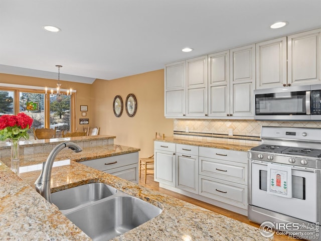 kitchen featuring sink, appliances with stainless steel finishes, white cabinetry, hanging light fixtures, and tasteful backsplash