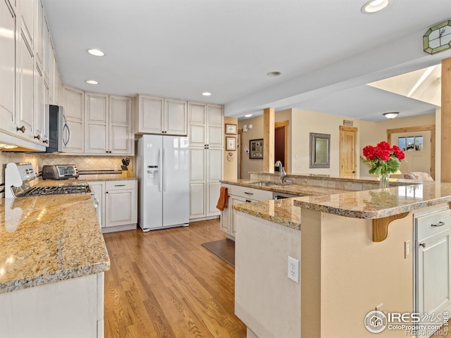 kitchen with appliances with stainless steel finishes, white cabinetry, sink, a breakfast bar area, and a large island