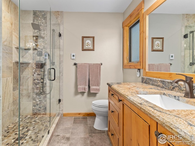 bathroom featuring vanity, a shower with shower door, and toilet