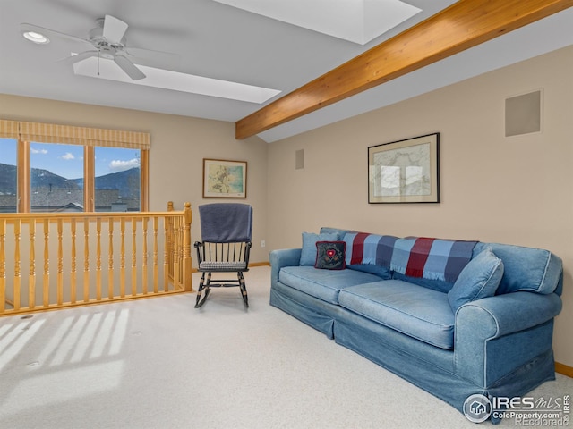 carpeted living room featuring a mountain view, vaulted ceiling with skylight, and ceiling fan