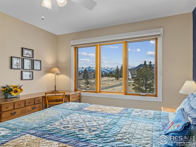 bedroom with multiple windows, a mountain view, and ceiling fan