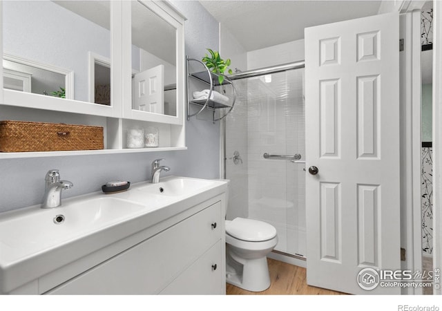 bathroom with a shower with door, vanity, hardwood / wood-style flooring, and toilet