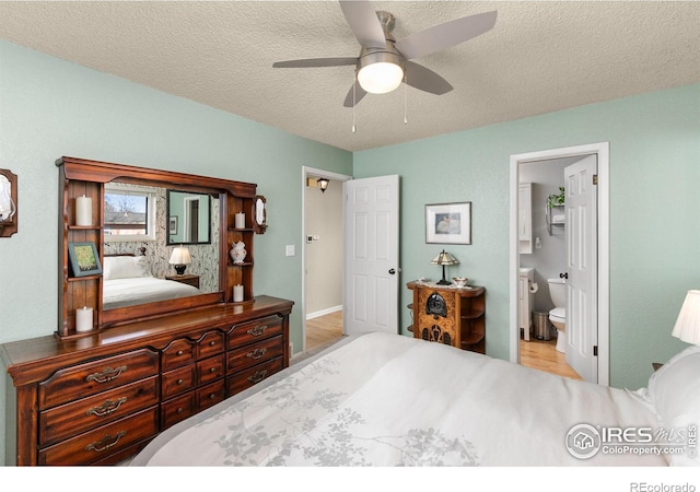 bedroom with ceiling fan, ensuite bath, and a textured ceiling