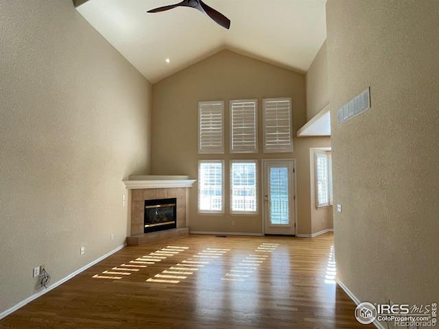 unfurnished living room with hardwood / wood-style flooring, a fireplace, high vaulted ceiling, and ceiling fan