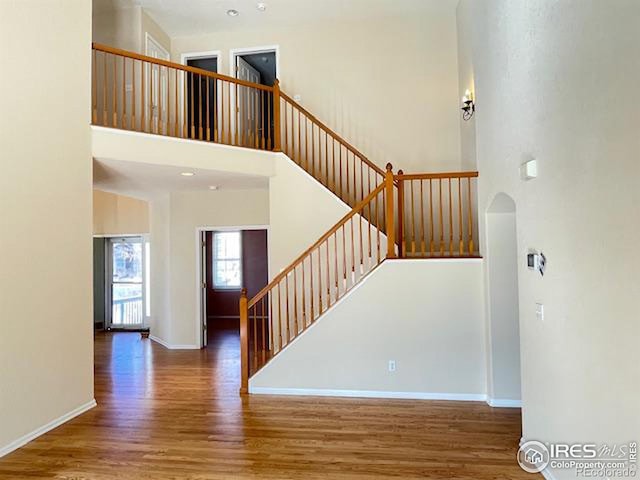 staircase featuring hardwood / wood-style flooring and a towering ceiling