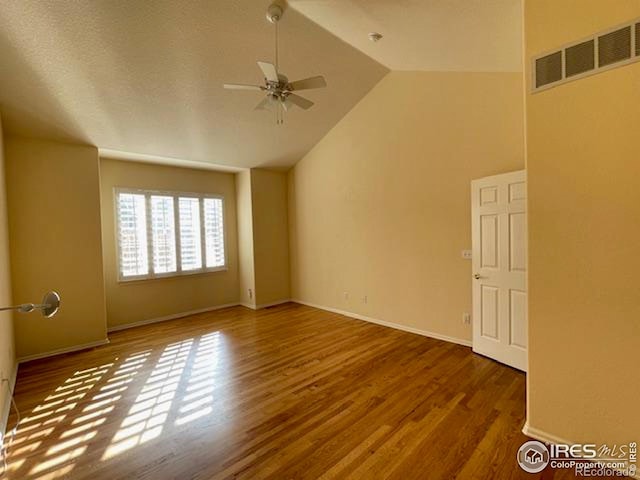 empty room with high vaulted ceiling, dark wood-type flooring, and ceiling fan