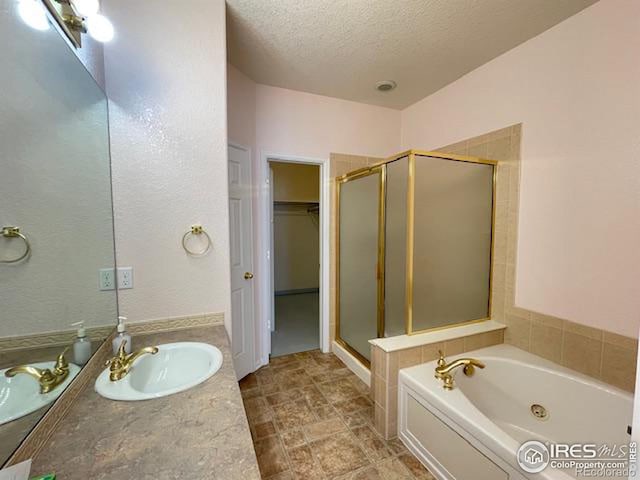 bathroom with vanity, independent shower and bath, and a textured ceiling