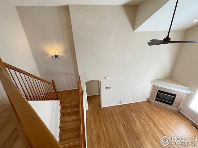 unfurnished living room with a tiled fireplace, hardwood / wood-style flooring, and ceiling fan