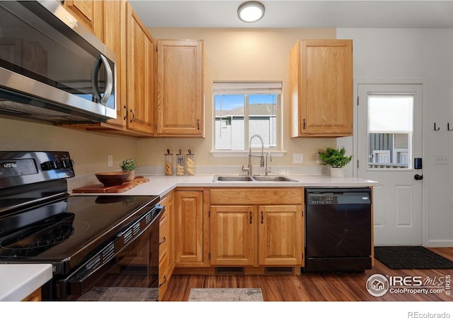 kitchen featuring sink, light brown cabinets, black appliances, and light wood-type flooring