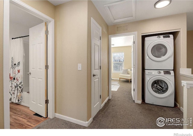 laundry room featuring stacked washer and dryer and carpet floors