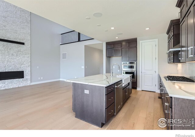 kitchen with visible vents, stainless steel appliances, dark brown cabinets, light wood-type flooring, and a sink