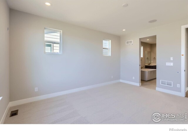 unfurnished bedroom with multiple windows, visible vents, and light colored carpet