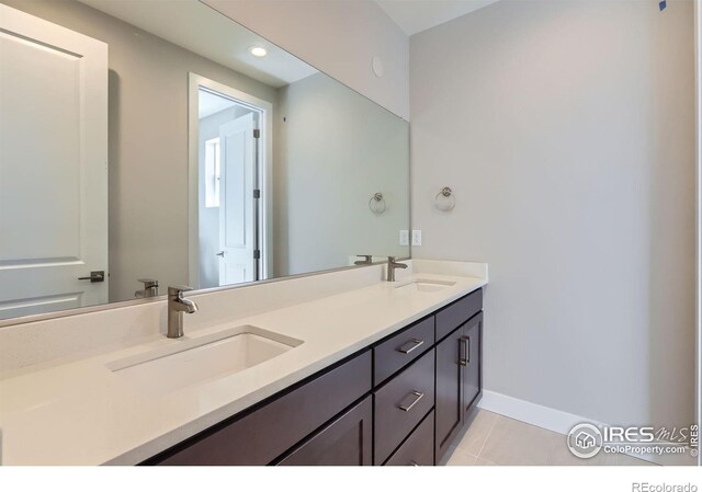 full bath featuring tile patterned flooring, a sink, baseboards, and double vanity