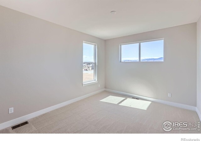 carpeted empty room with visible vents and baseboards