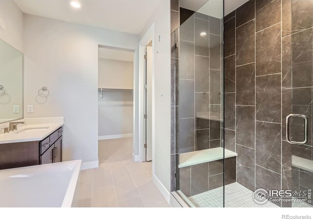 full bathroom featuring vanity, baseboards, tile patterned floors, a stall shower, and a walk in closet