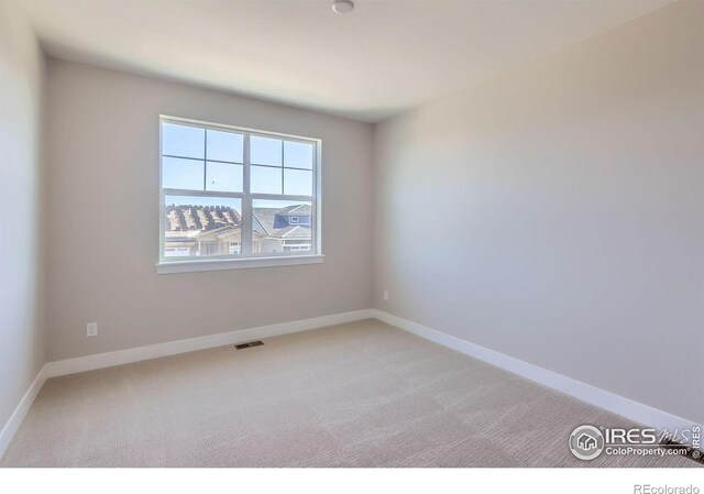 empty room featuring baseboards, visible vents, and light colored carpet