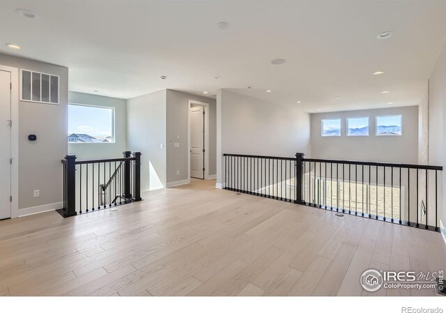 spare room featuring a wealth of natural light, visible vents, light wood-style flooring, and baseboards