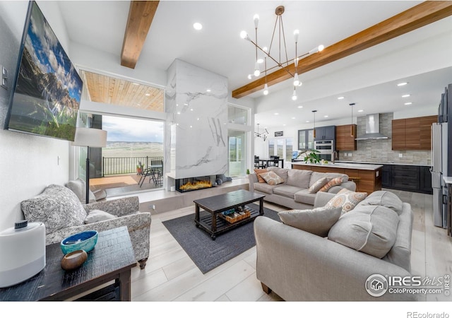 living room featuring a high end fireplace, an inviting chandelier, and beam ceiling