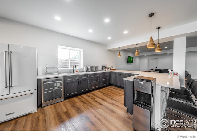 kitchen featuring sink, hanging light fixtures, kitchen peninsula, white fridge, and beverage cooler