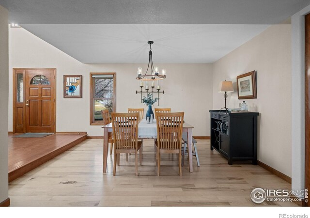 dining area with light hardwood / wood-style flooring and a notable chandelier