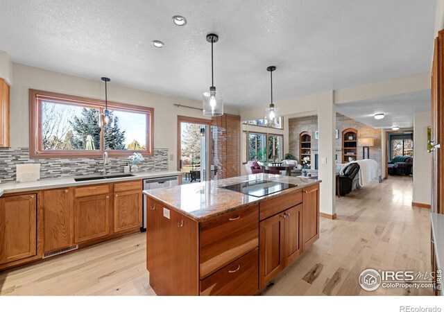 kitchen featuring a center island, light hardwood / wood-style floors, sink, black electric cooktop, and pendant lighting