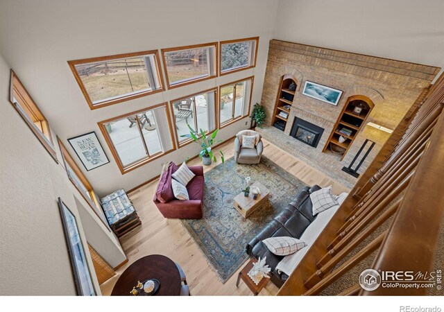 living room with a tiled fireplace, wood-type flooring, and a towering ceiling