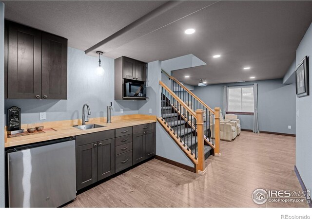 kitchen with dishwashing machine, sink, butcher block counters, decorative light fixtures, and black microwave