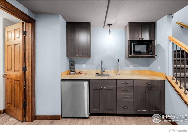 kitchen with dishwashing machine, sink, butcher block counters, black microwave, and dark brown cabinets