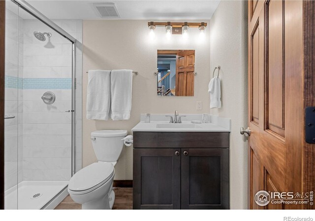 bathroom with toilet, vanity, and an enclosed shower