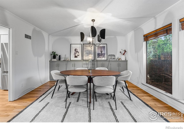 dining space with hardwood / wood-style flooring, ornamental molding, and an inviting chandelier