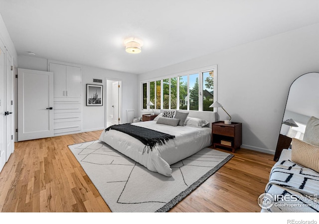 bedroom featuring ensuite bathroom and light hardwood / wood-style flooring