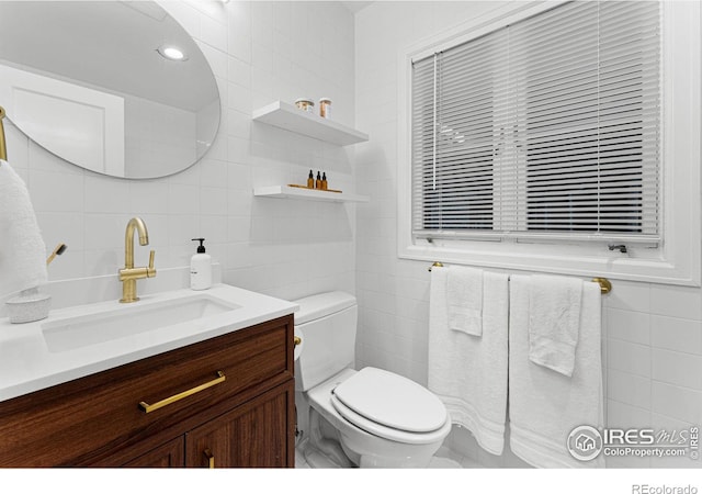 bathroom featuring tile walls, vanity, and toilet