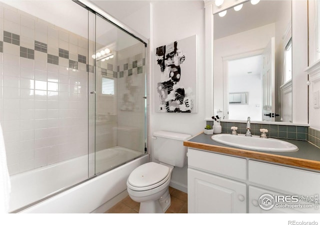 full bathroom featuring tile patterned flooring, vanity, bath / shower combo with glass door, and toilet