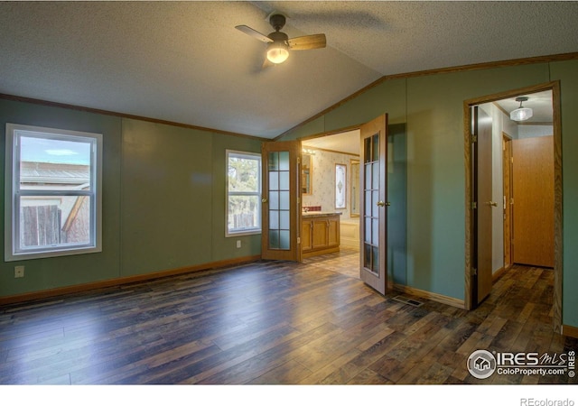 spare room with lofted ceiling, dark hardwood / wood-style floors, ornamental molding, a textured ceiling, and french doors